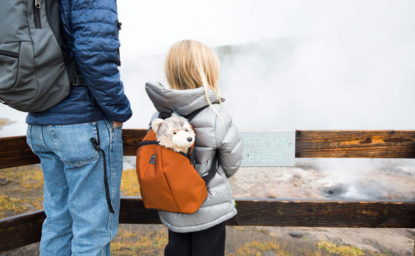 A child wearing The Sprout accompanied by their parent at a geyser.